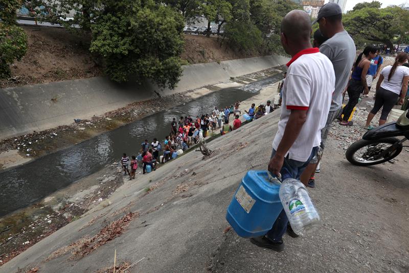 Caraqueños recogen agua en el río Guaire por el apagón